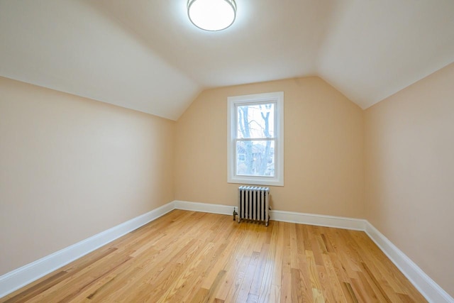 bonus room with lofted ceiling, light wood-style floors, radiator heating unit, and baseboards