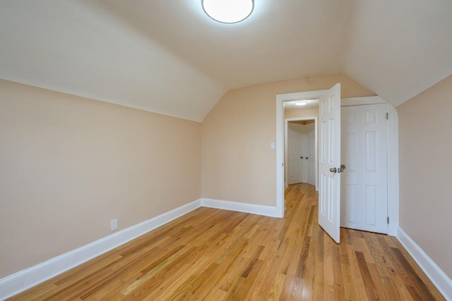 additional living space featuring lofted ceiling, light wood finished floors, and baseboards