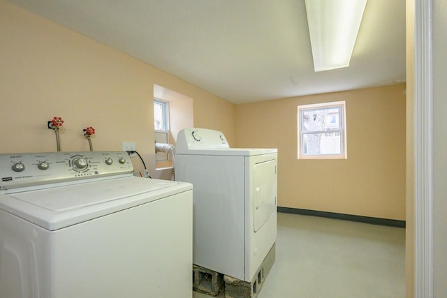 clothes washing area with laundry area, separate washer and dryer, and baseboards