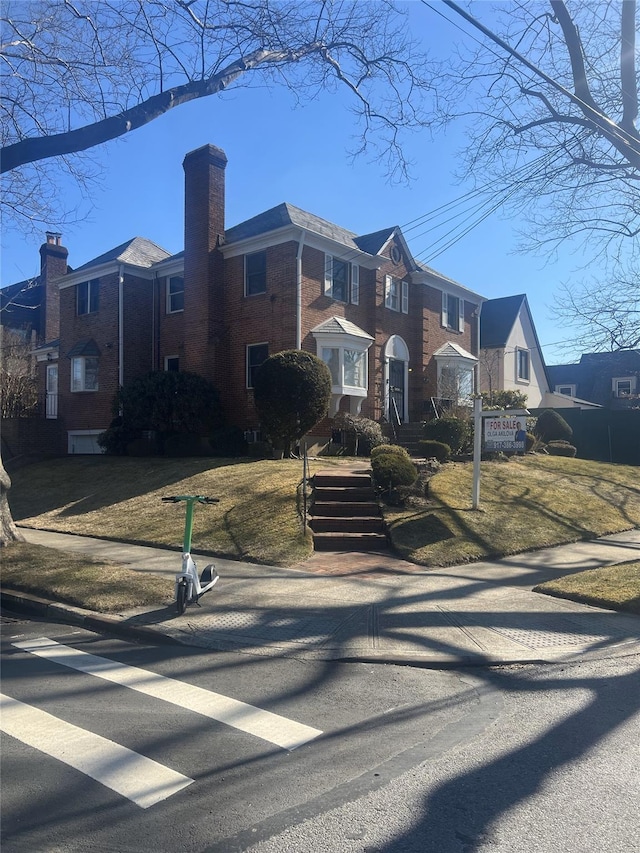 view of front facade with brick siding, a chimney, and a residential view