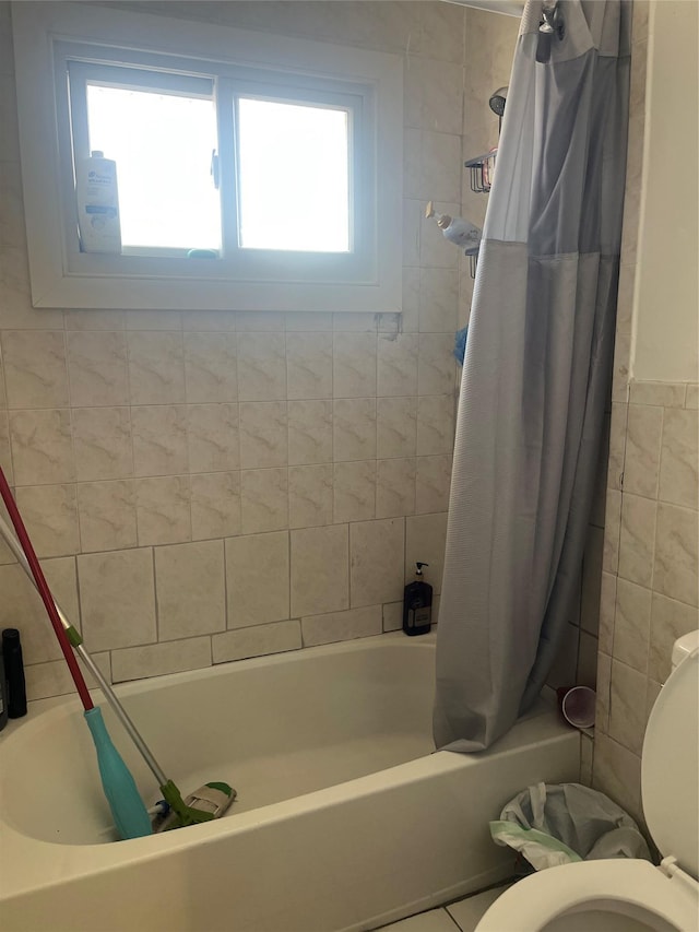 bathroom with toilet, tile walls, and shower / bathtub combination with curtain