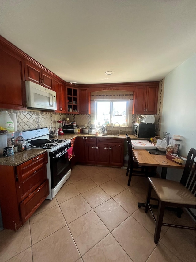 kitchen with tasteful backsplash, white microwave, stainless steel microwave, a sink, and gas stove