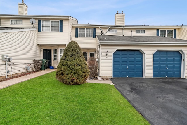 view of property featuring driveway, a garage, a chimney, and a front yard