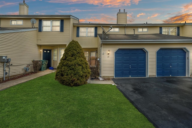 multi unit property with a front lawn, driveway, a chimney, and an attached garage