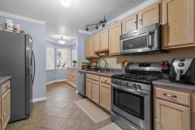 kitchen featuring dark countertops, appliances with stainless steel finishes, ornamental molding, light brown cabinets, and a sink