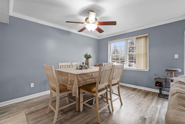 dining space with baseboards, wood finished floors, and crown molding