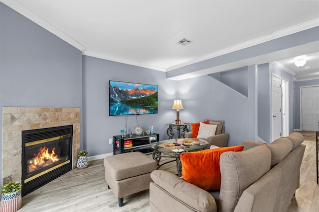 living area featuring a fireplace, visible vents, ornamental molding, light wood-style floors, and baseboards