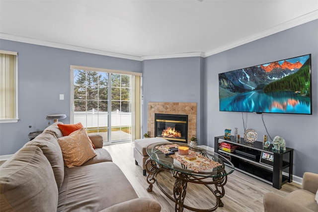 living room with baseboards, a tiled fireplace, wood finished floors, and crown molding