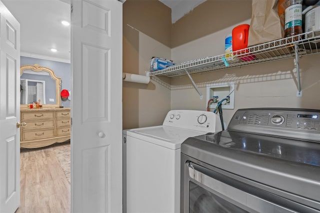 laundry area featuring laundry area, washing machine and dryer, crown molding, and wood finished floors