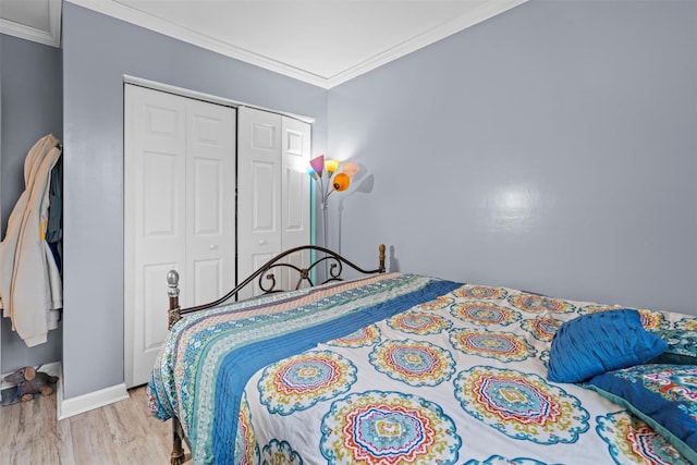 bedroom featuring a closet, crown molding, baseboards, and wood finished floors