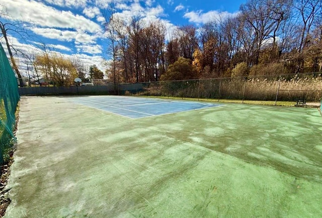 view of tennis court with community basketball court and fence