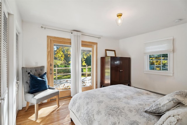 bedroom with a baseboard heating unit and light wood-style floors