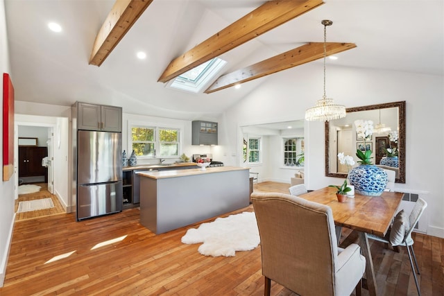 dining room with beamed ceiling, a notable chandelier, light wood-style flooring, recessed lighting, and a skylight