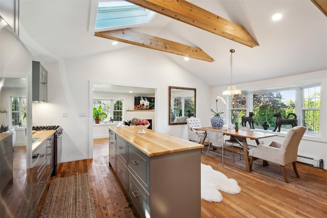 kitchen featuring beam ceiling, gray cabinetry, hardwood / wood-style floors, wooden counters, and stainless steel gas range