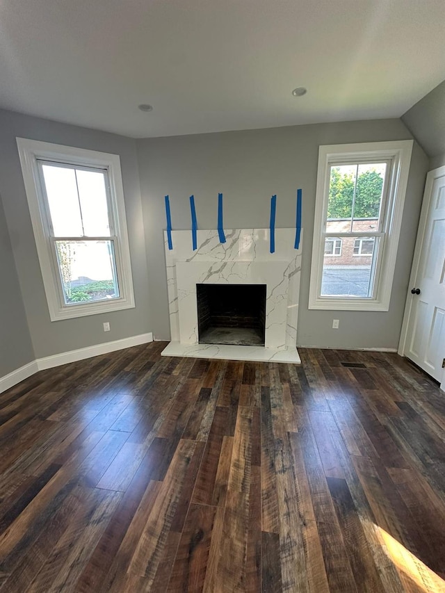 unfurnished living room featuring vaulted ceiling, hardwood / wood-style floors, a fireplace, and baseboards