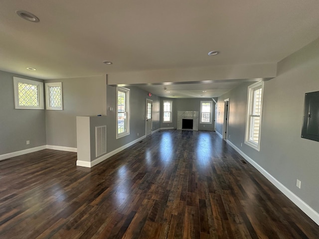 unfurnished living room featuring dark wood-style floors, a fireplace, visible vents, and baseboards