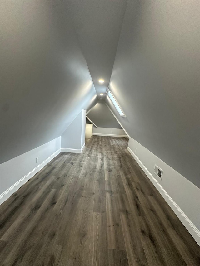 additional living space with lofted ceiling, visible vents, baseboards, and dark wood-type flooring