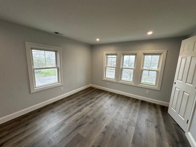 spare room featuring baseboards, visible vents, dark wood-style flooring, and recessed lighting