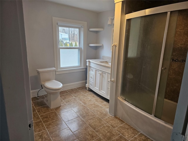 bathroom featuring toilet, enclosed tub / shower combo, baseboards, and vanity