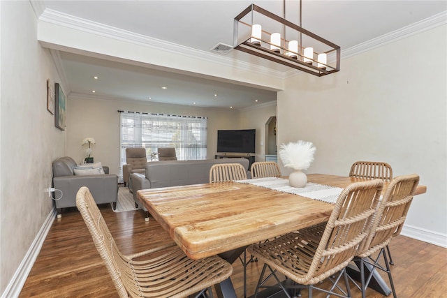 dining room with arched walkways, crown molding, visible vents, wood finished floors, and baseboards