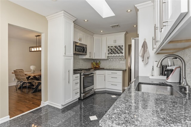 kitchen featuring recessed lighting, stainless steel appliances, granite finish floor, a sink, and baseboards