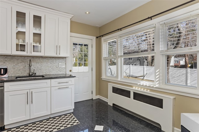 kitchen with baseboards, white cabinets, glass insert cabinets, granite finish floor, and a sink