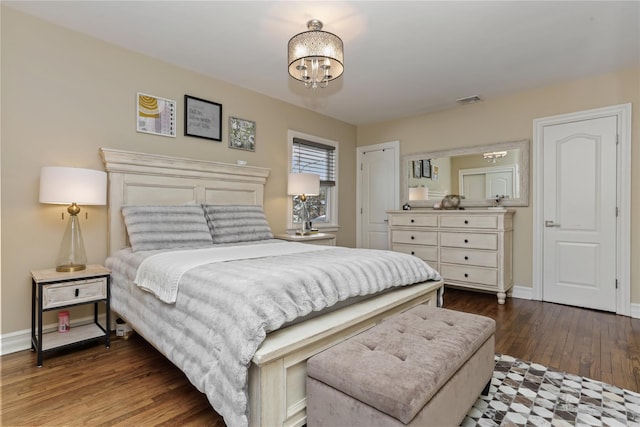 bedroom featuring a chandelier, wood finished floors, visible vents, and baseboards