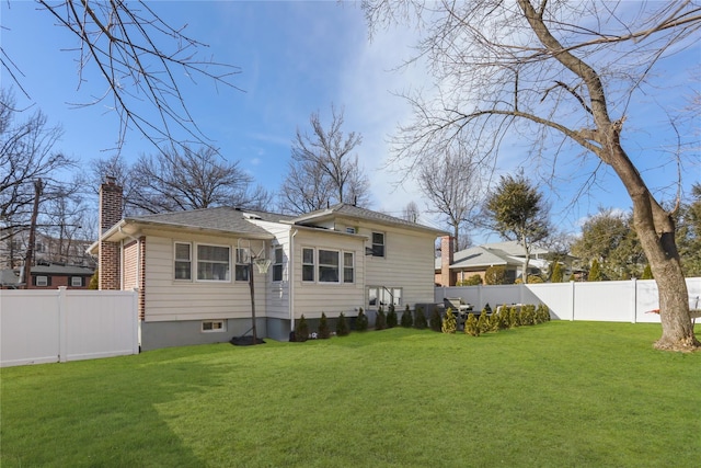 back of house with a lawn, a chimney, and a fenced backyard