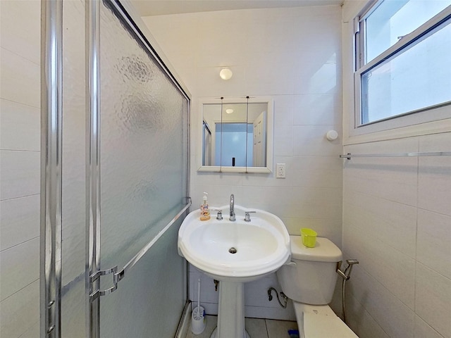 full bathroom featuring toilet, a shower stall, a sink, and tile walls