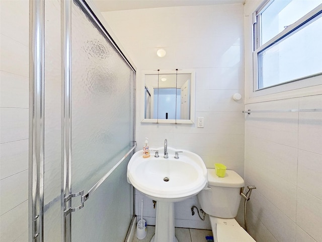 full bathroom with toilet, a stall shower, and tile walls