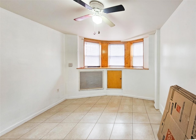 unfurnished room with radiator, baseboards, a ceiling fan, and light tile patterned flooring