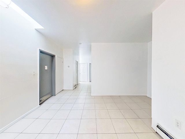 empty room featuring light tile patterned floors, a baseboard radiator, and baseboards