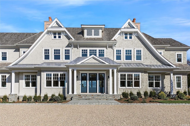 view of front of house featuring a chimney, a standing seam roof, and metal roof