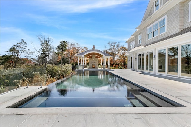 view of swimming pool with a patio and a warm lit fireplace