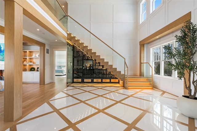 foyer with stairs, a decorative wall, plenty of natural light, and a towering ceiling