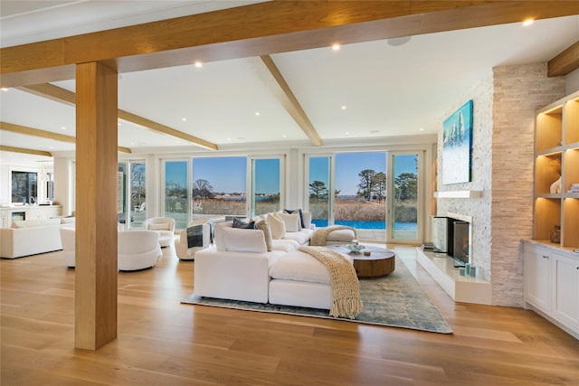 living room with a stone fireplace, beamed ceiling, recessed lighting, and light wood-style floors