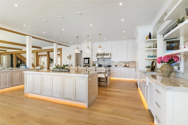 kitchen featuring a sink, light wood-style floors, a spacious island, and decorative backsplash