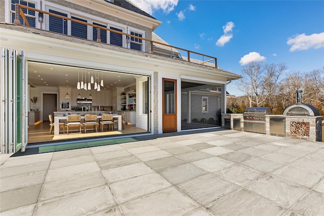 rear view of property with exterior kitchen, a balcony, and a patio area