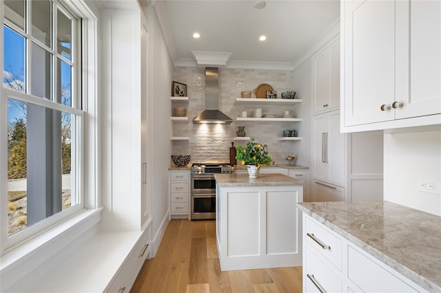 kitchen with tasteful backsplash, range with two ovens, light wood-style floors, wall chimney exhaust hood, and open shelves