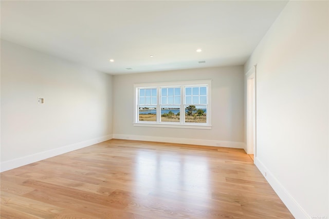 empty room featuring light wood finished floors, recessed lighting, and baseboards