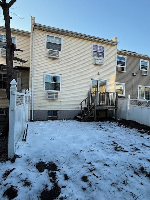 snow covered rear of property featuring fence