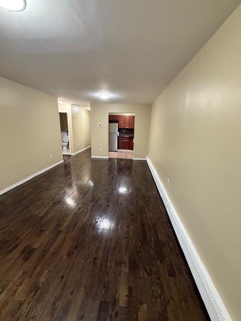 unfurnished living room featuring dark wood-style floors and baseboards