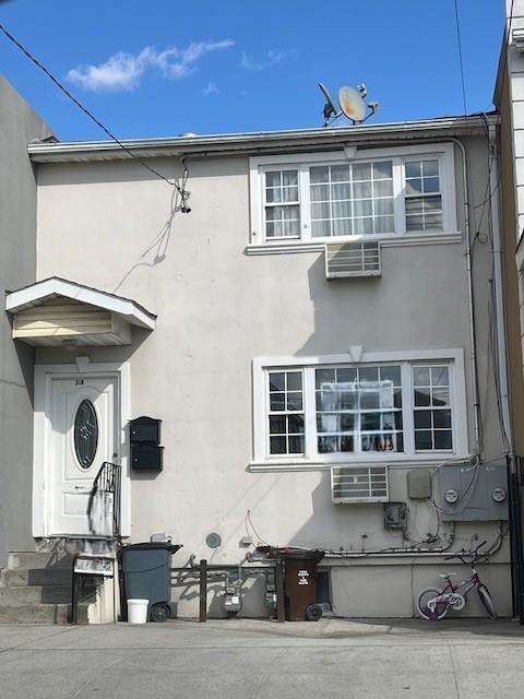 exterior space with a wall mounted air conditioner and stucco siding