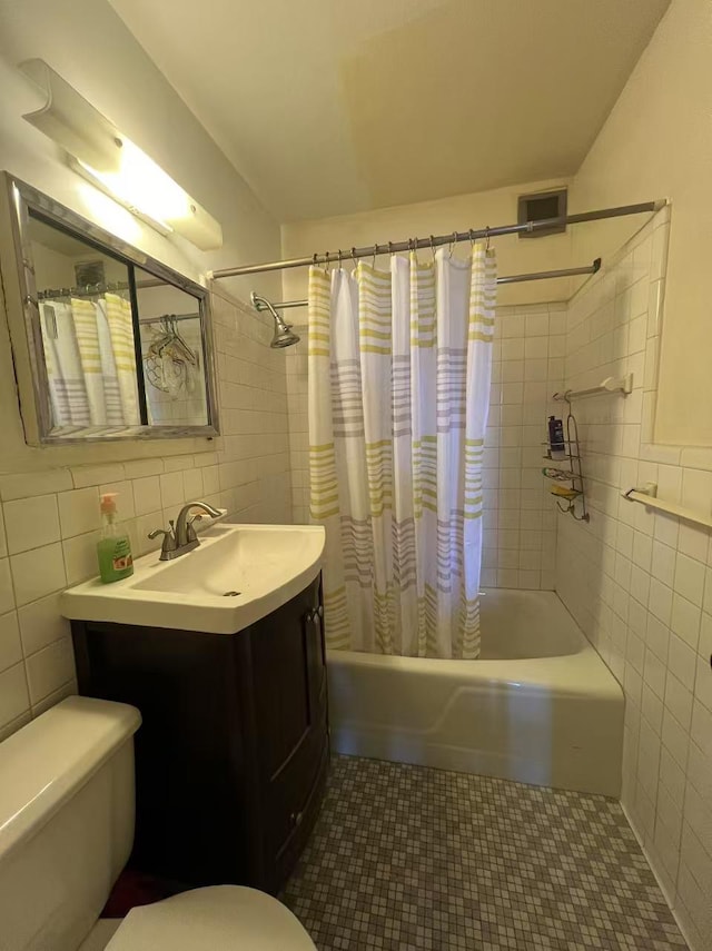 bathroom featuring toilet, vanity, tile walls, tile patterned floors, and shower / bathtub combination with curtain