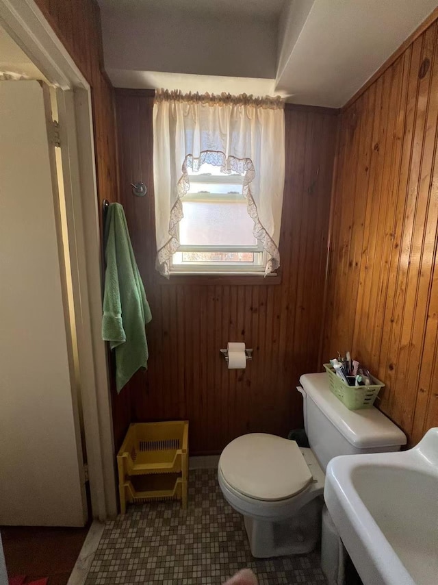 half bath featuring a sink, wood walls, and toilet