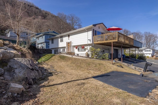 back of property with a yard, a wooden deck, and driveway