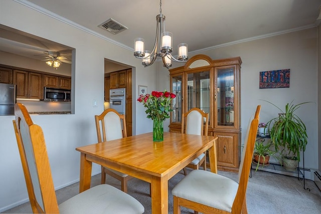 dining area with ceiling fan with notable chandelier, crown molding, light colored carpet, and visible vents