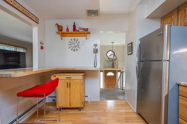 kitchen with light wood finished floors, visible vents, baseboard heating, brown cabinets, and freestanding refrigerator