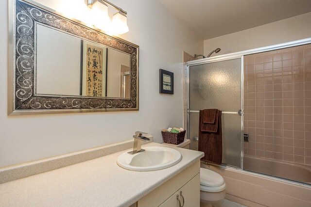 bathroom featuring vanity, toilet, and combined bath / shower with glass door