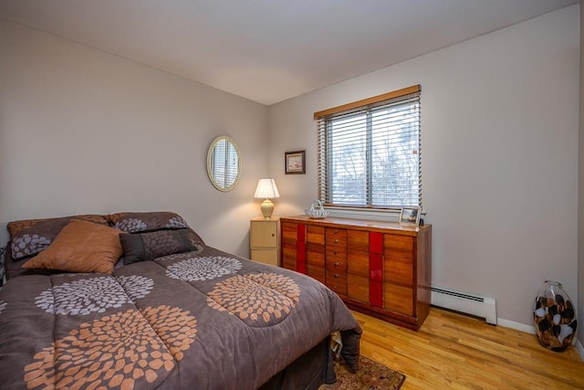 bedroom with a baseboard heating unit and light wood finished floors